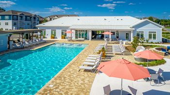 a swimming pool with chairs and umbrellas and pergola at Anthem Apartments in Huntsville, Alabama